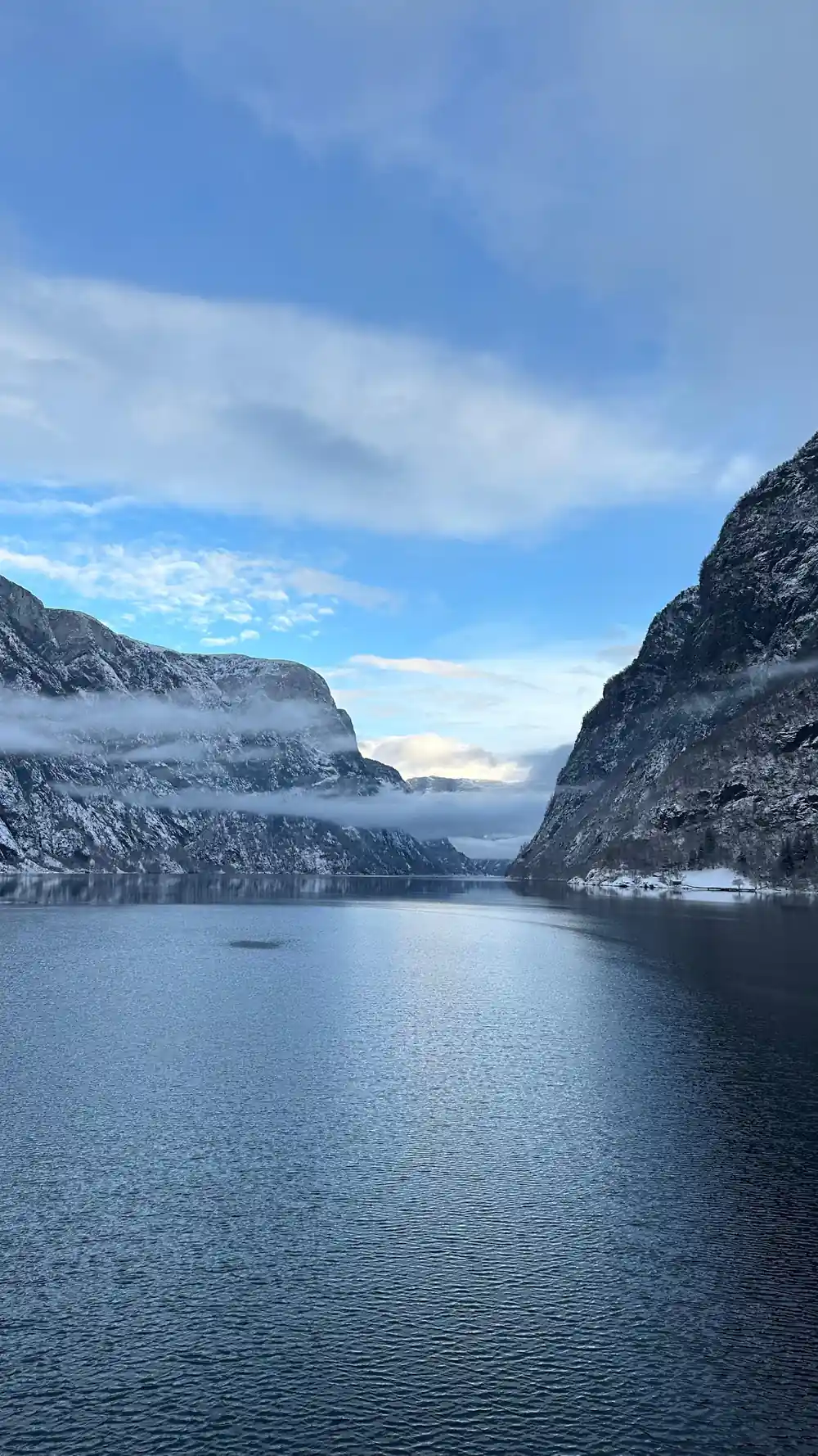 Cloud lying halfway down the fjord walls above dark water