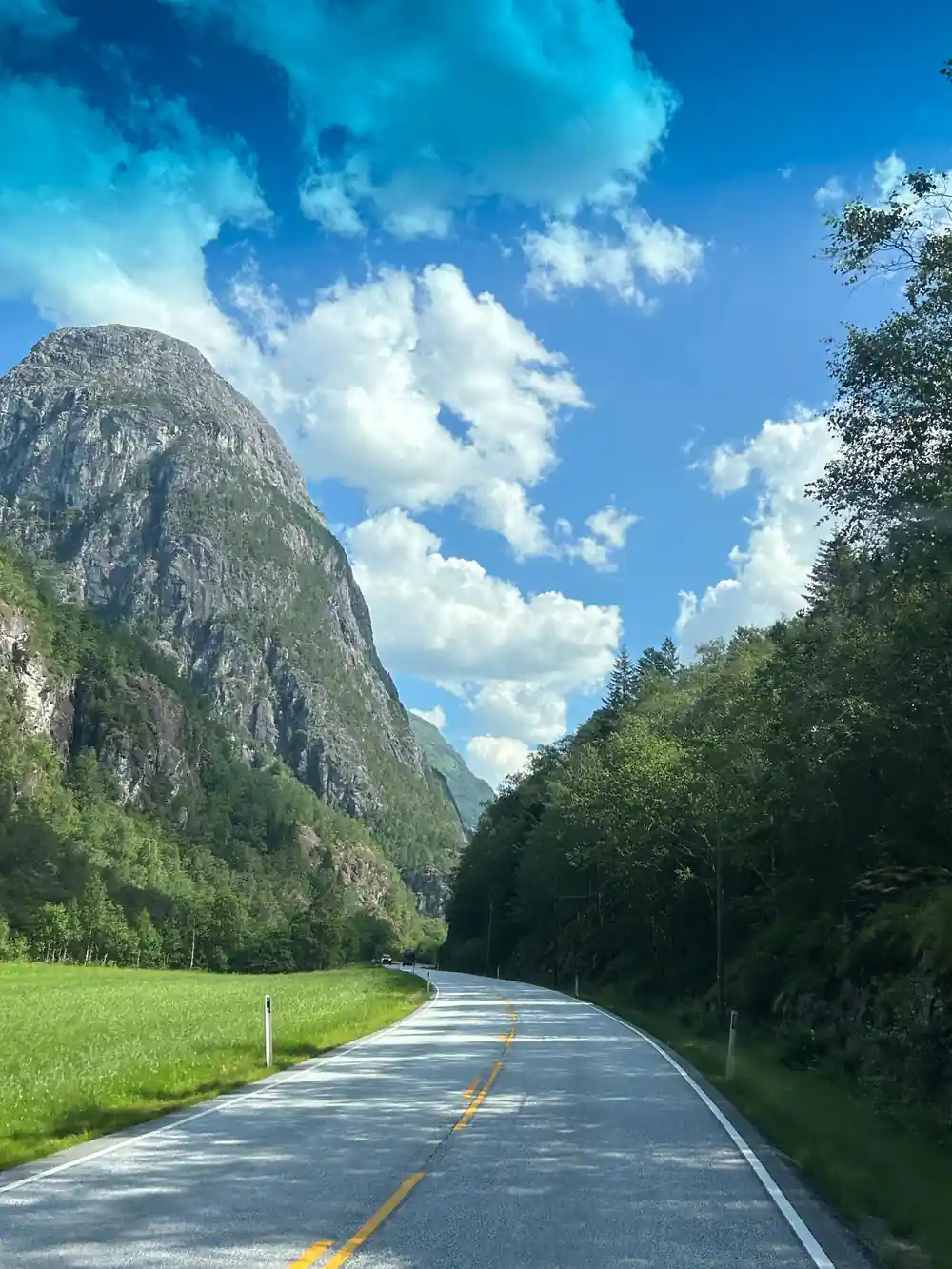 An empty road running along the valley floor beneath rock walls