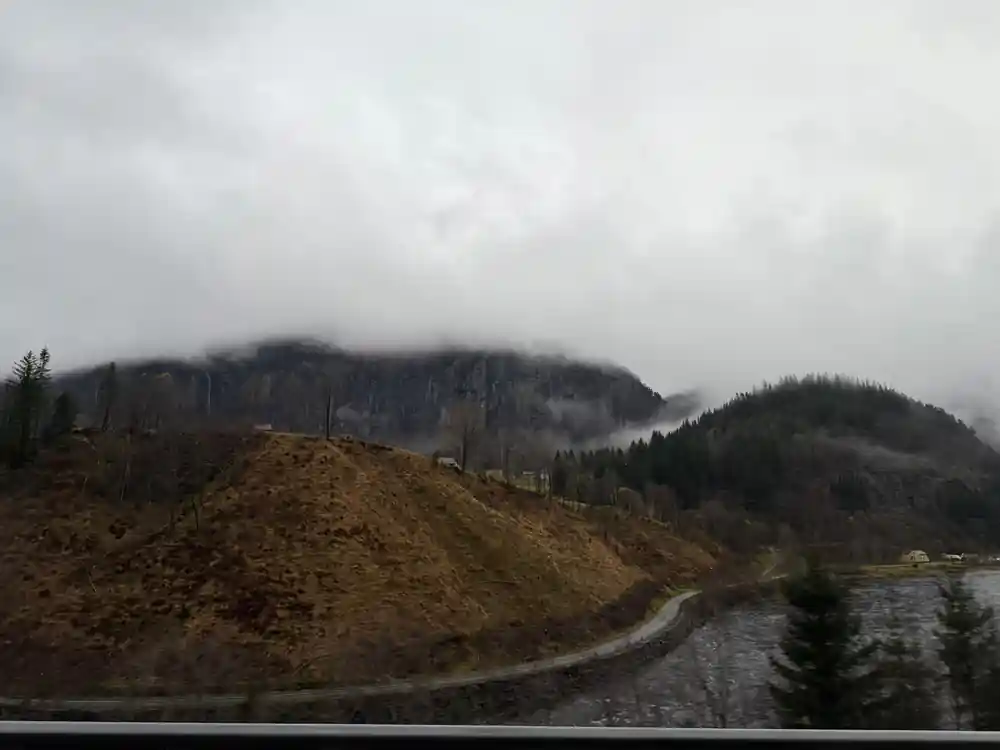 A gravel road climbing through low cloud on a bare hillside