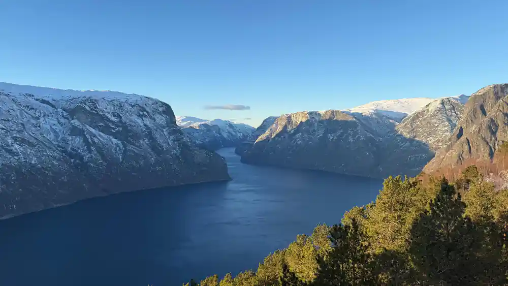 Late sun on the far wall of the fjord above dark blue water