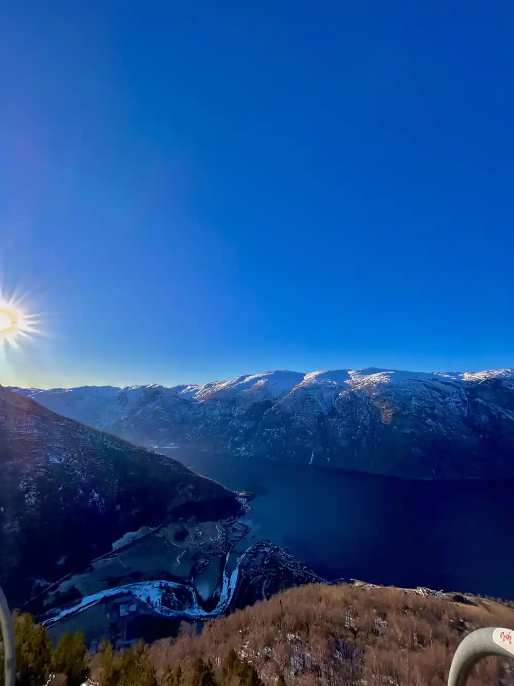 Low sun breaking over a ridge above the dark fjord