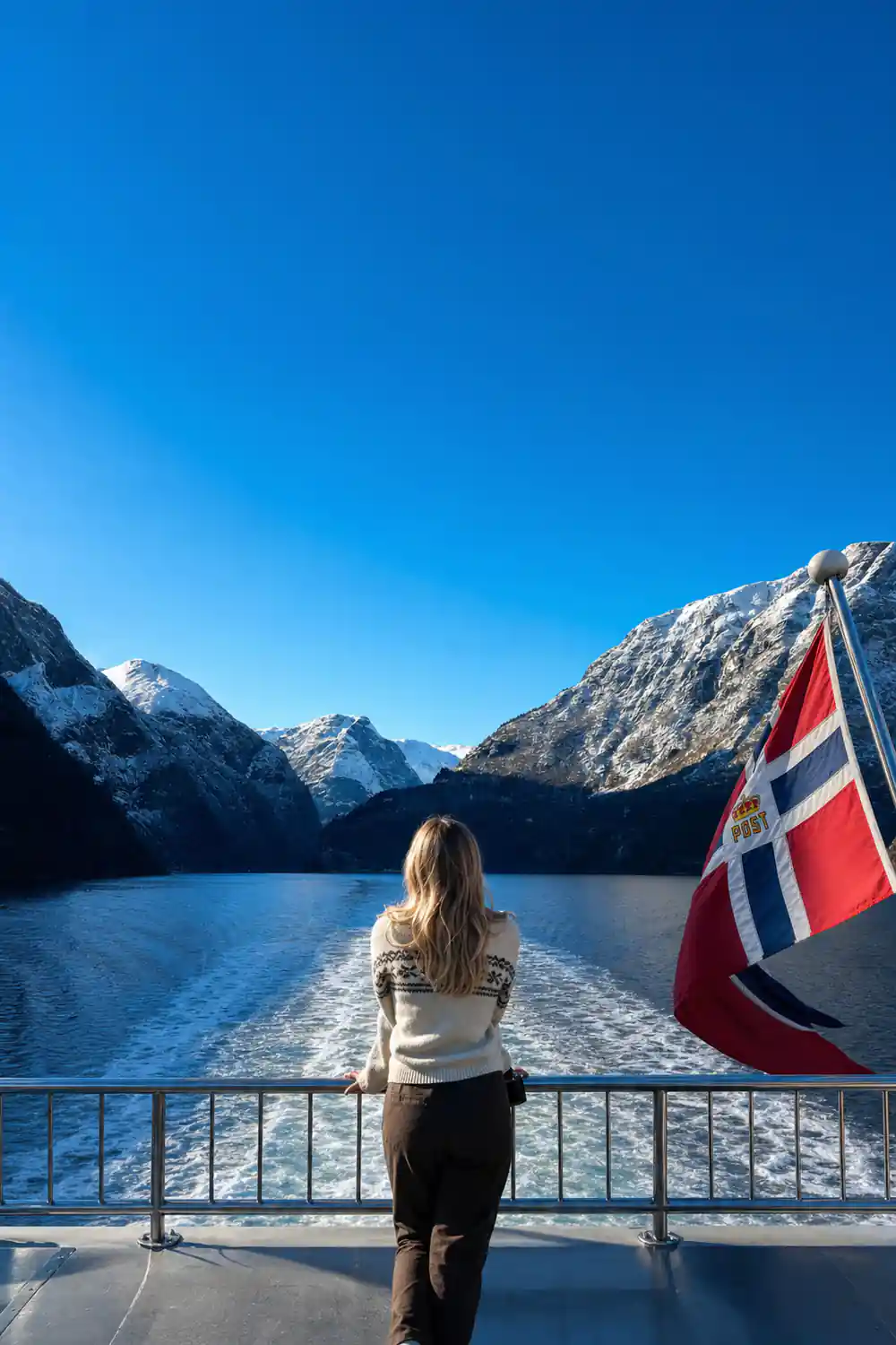 The Norwegian flag against snow-covered mountains from the deck
