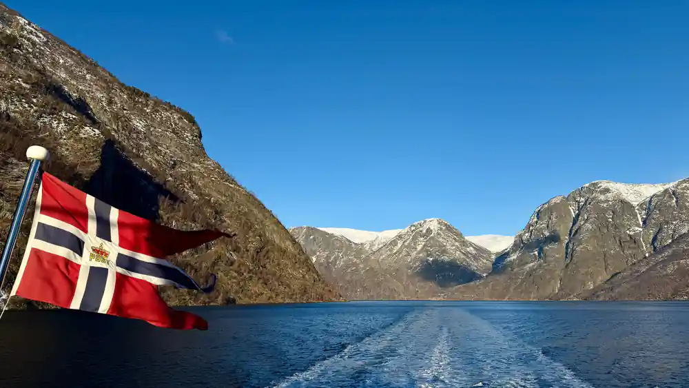 The Norwegian flag at the stern with the boat's wake behind
