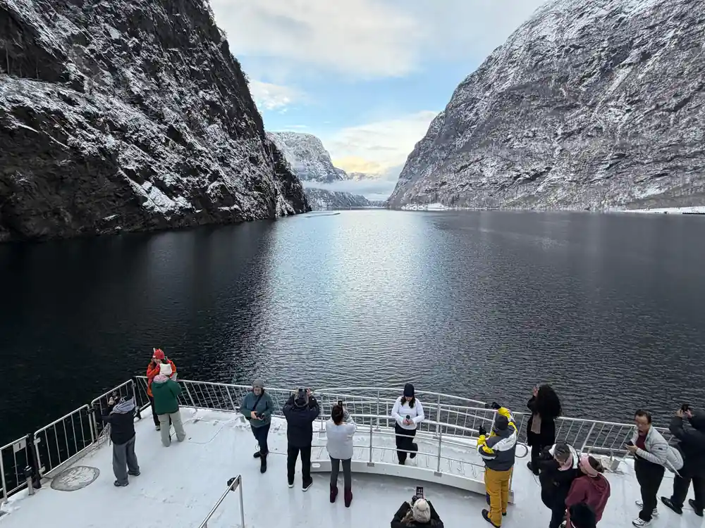 Passengers at the bow rail as the boat runs into the narrow arm