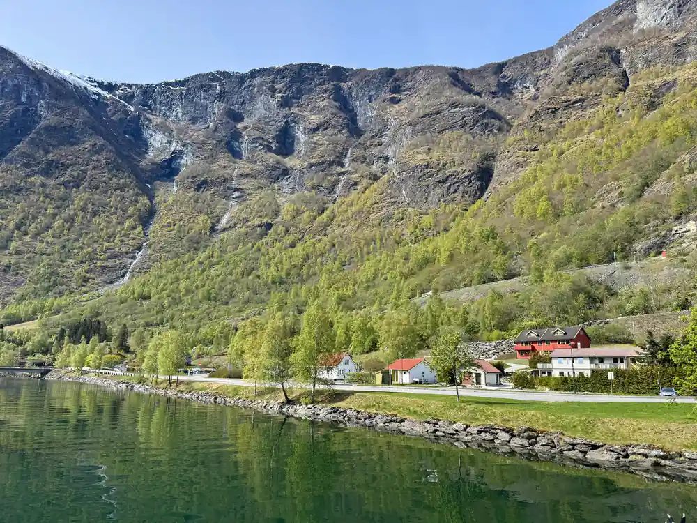 A small settlement on the shore beneath a long rock wall