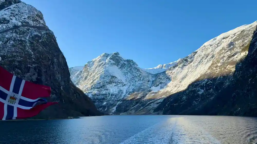 Snow on the peaks above still water at the head of the fjord