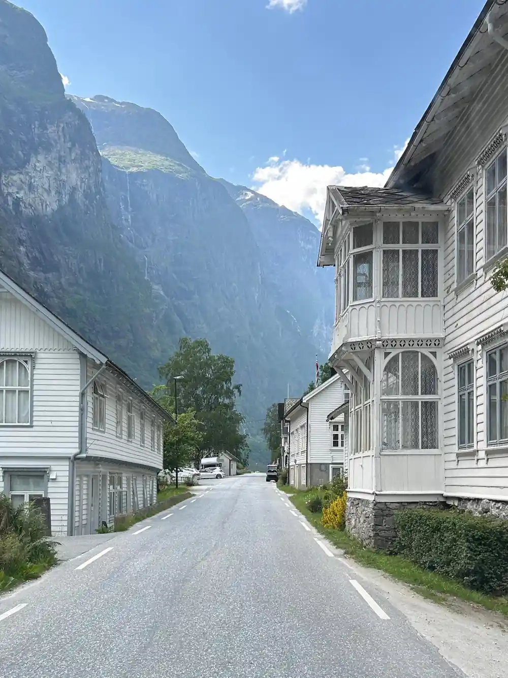 A street of white timber houses under a fjord mountain