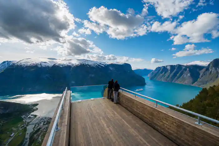 Two people at the rail of the Stegastein platform above a turquoise fjord