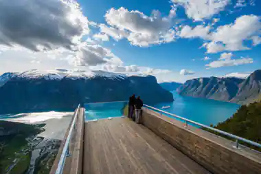 Two people at the rail of the Stegastein platform above a turquoise fjord