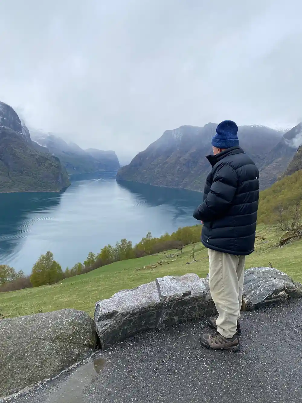 A visitor at a roadside stone looking down the fjord