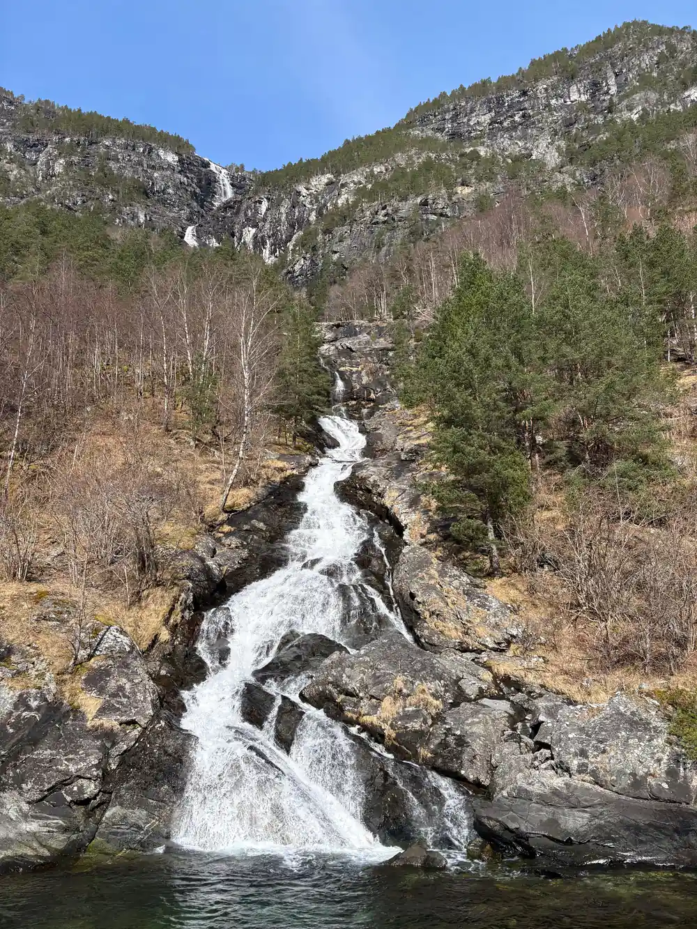 A white torrent coming down through bare trees and rock