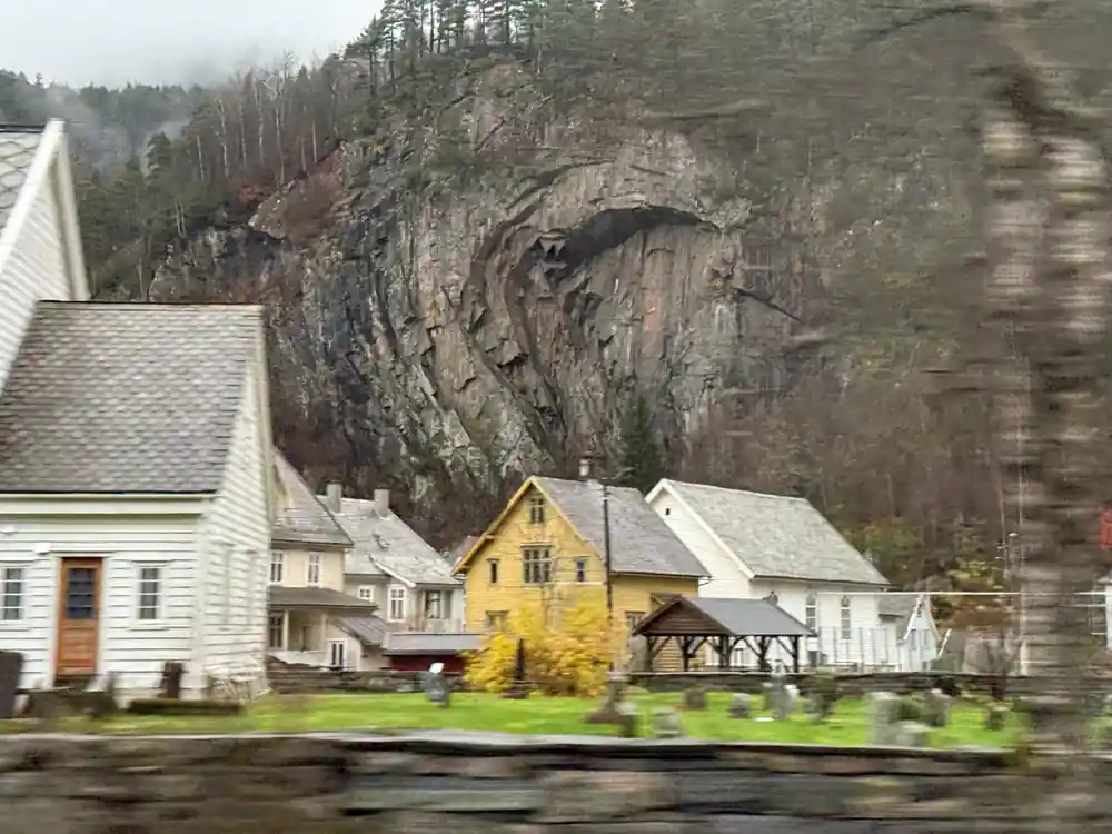 White and yellow timber houses beneath an overhanging rock face