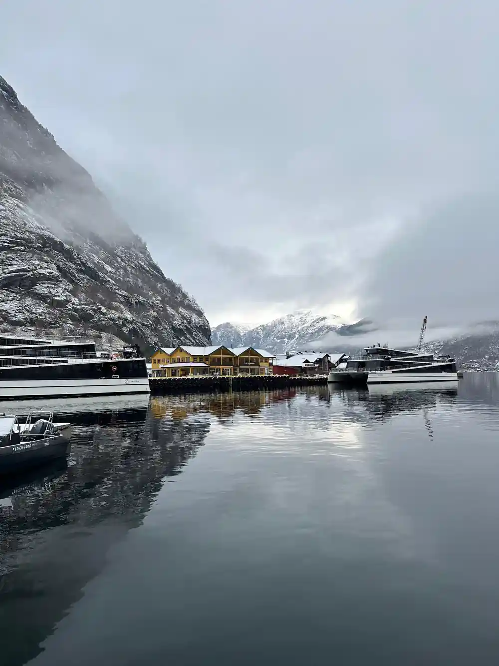 Yellow warehouses and moored boats at a quay under low cloud